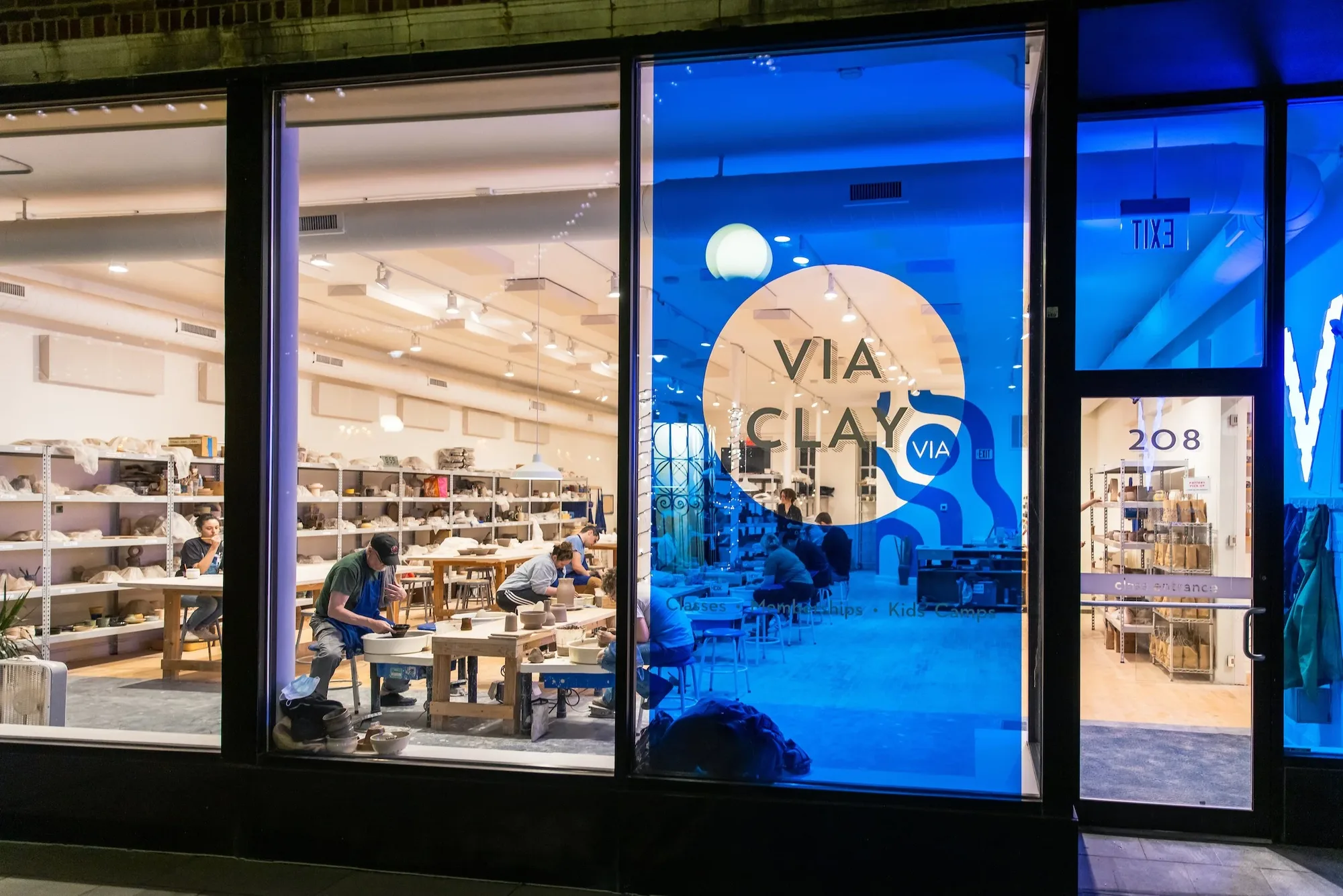 The ViaClay storefront on Marion Street in Oak Park at night, with students working inside
