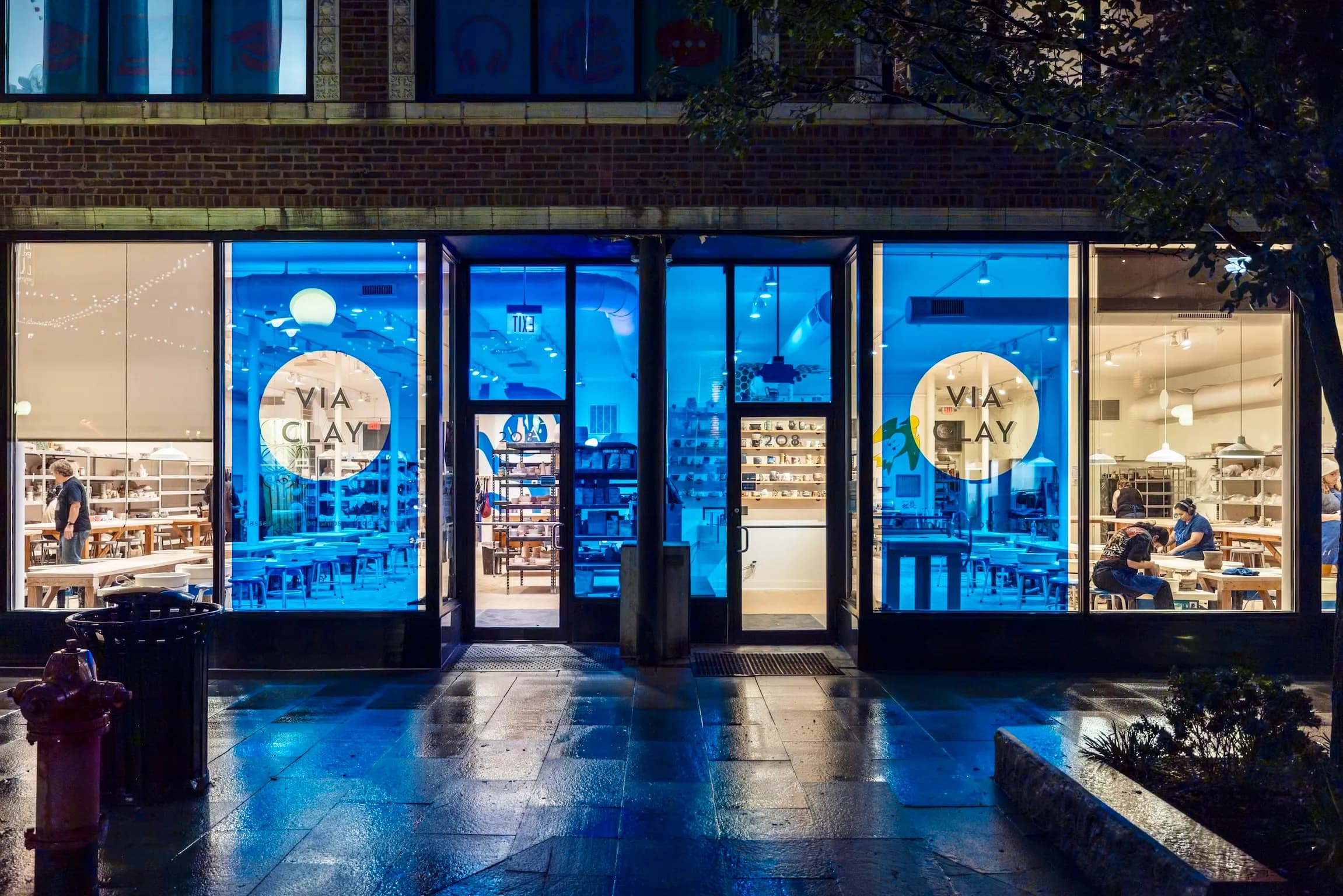 The ViaClay storefront on Marion Street in Oak Park at night, with students working inside
