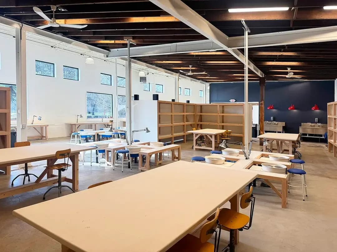 ViaClay Member Studio: worktables, pottery wheels and wooden member shelves under a timbered ceiling
